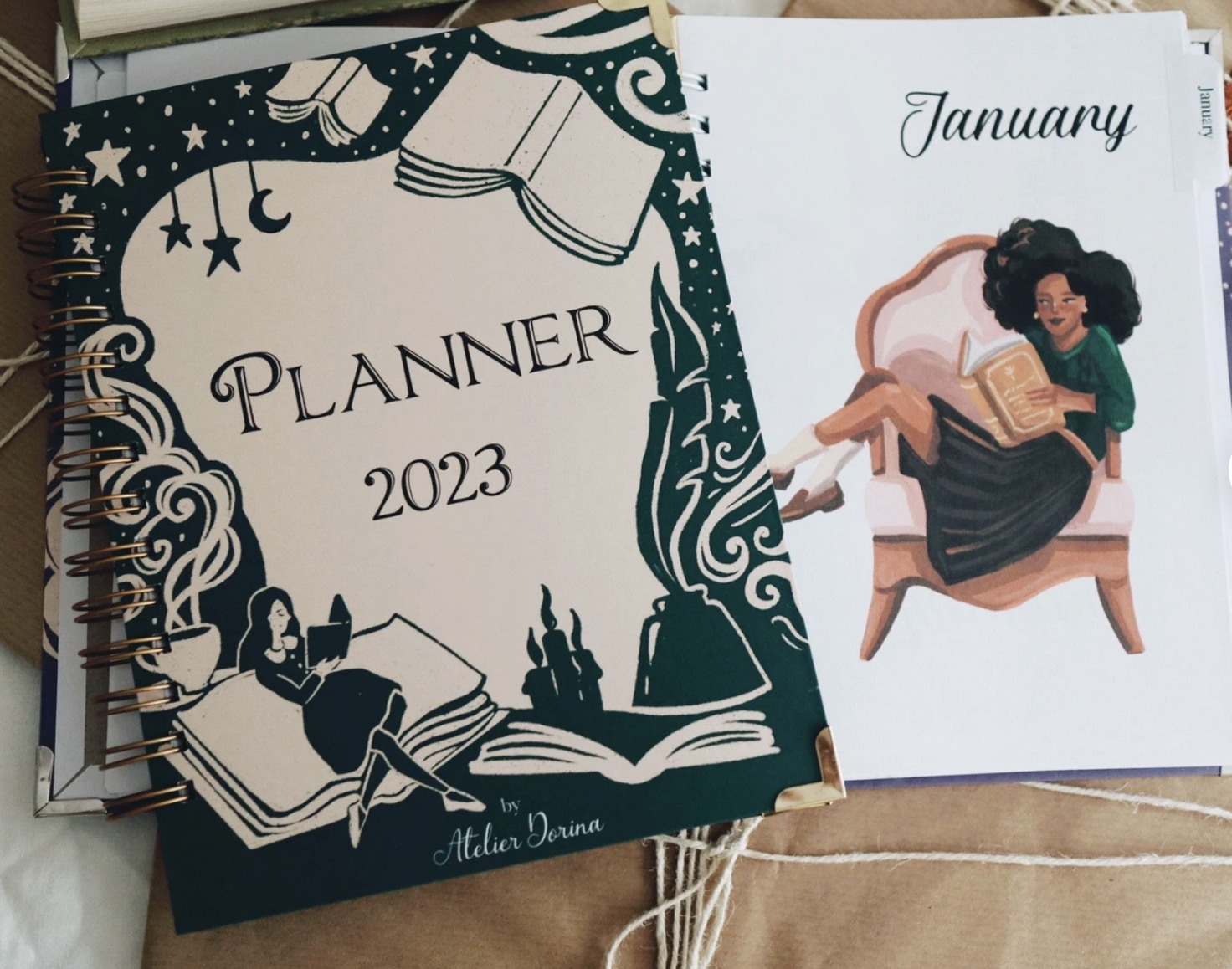 cover of the 2023 book lover planner next to one of the illustrations inside the planner, of a woman reading on a chair