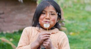 Indigenous brown-skinned child blows on a dandelion