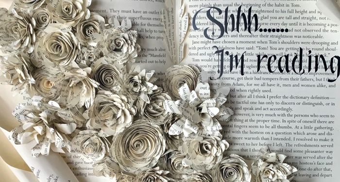 An old book opened to a sculpture of florals made of old pages.