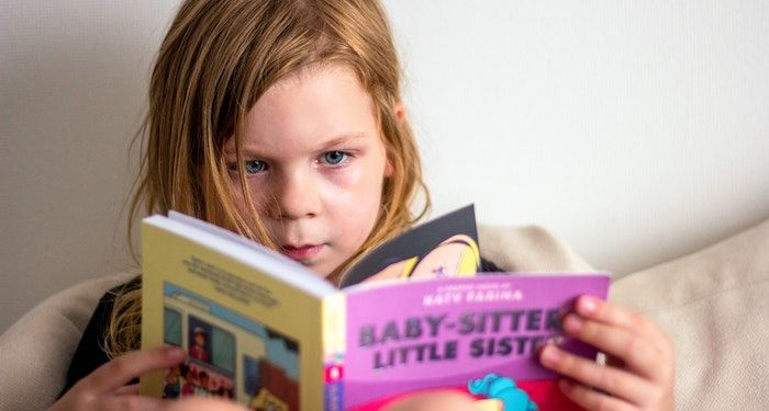 a photo of a kid reading a Baby-Sitters Little Sister graphic novels