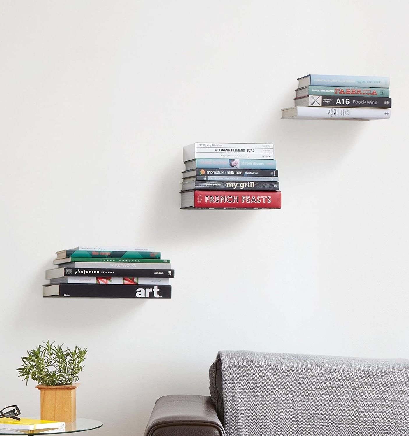 three stacks of books that appear to be floating on the wall