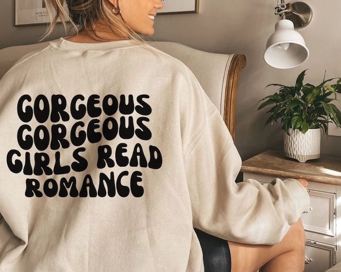 White sweatshirt with bubble letters on the back that read in all caps "GORGEOUS GORGEOUS GIRLS READ ROMANCE"