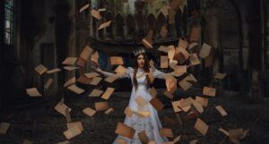 lighter skinned woman with crown and the pages of a book in midair