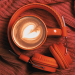 a photo of headphones and a latte on a red knitted fabric