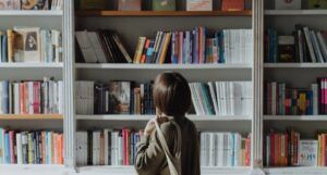 person with bob haircut looking at a large bookshelf