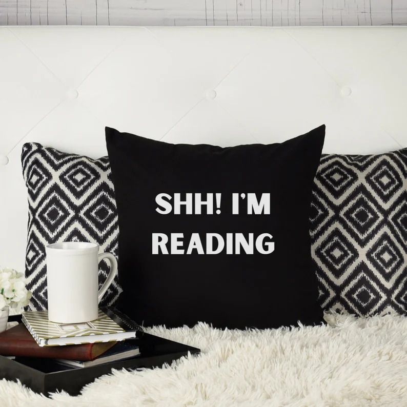 Photo of a black pillow with the text Shh! I'm reading on it.