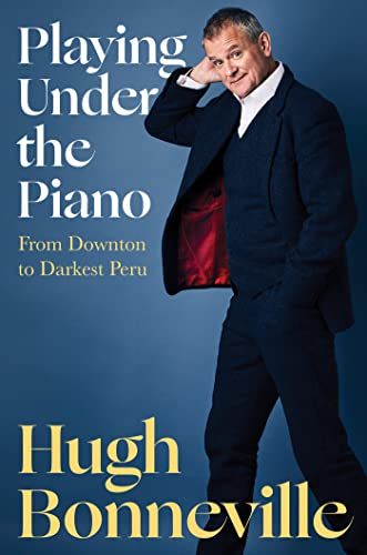 cover of Playing Under the Piano: From Downton to Darkest Peru by Hugh Bonneville; photo of the actor in a dark blue suit with close-cropped gray hair