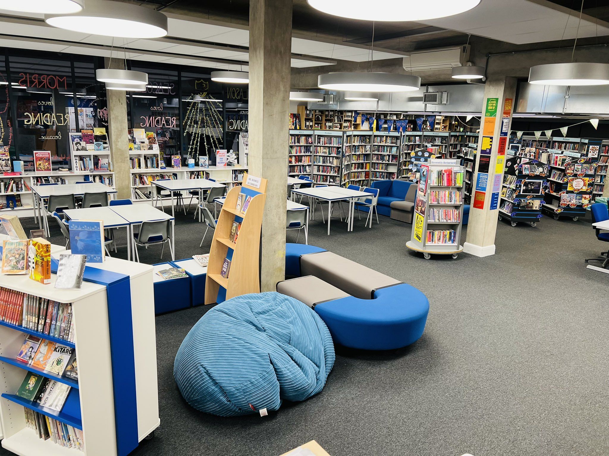 A school library containing bean bag, shelves and tables and books 