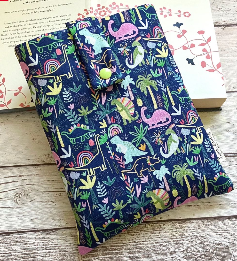 Image of a colorful fabric book holder featuring dinosaurs and plants. 
