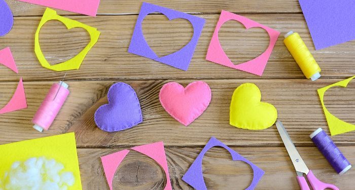 pink, yellow, and purple craft supplies, including construction paper with hearts cut out