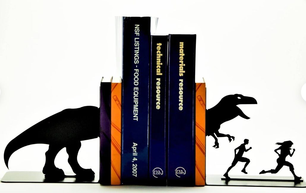 Image of bookends. They're black and metal and feature a t-rex chasing 2 people. 