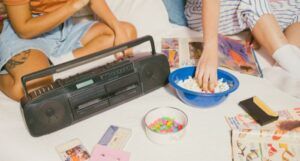 Vintage style image of two teen girls with a bowl of popcorn, boombox, and cassette tapes