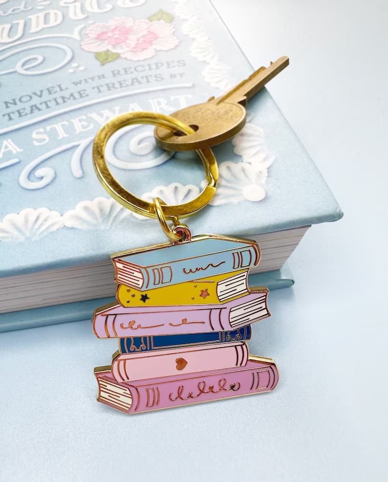Photo of a keychain shaped like a stack of books in various colours, blue, yellow, purple and pink with stars and hearts on the spines.