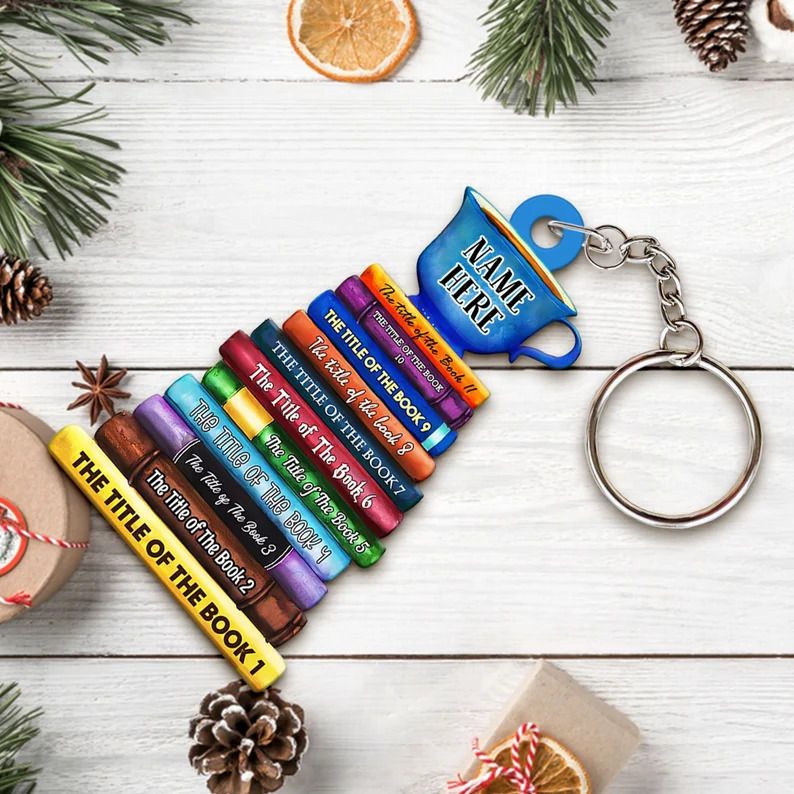 Photo of a keychain with a stack of books with several titles and a cup of tea on top.