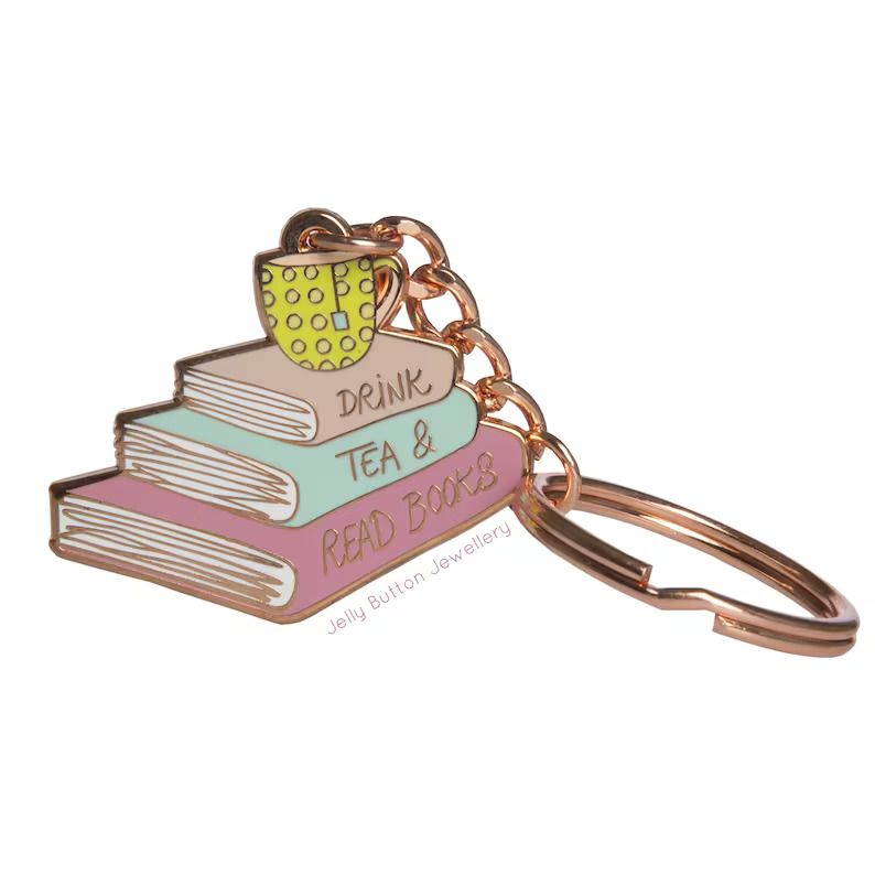 Photo of a keychain shaped like a stack of books in different colours, a tea mug on top of the stack and the words Drink tea & read books on the spines.
