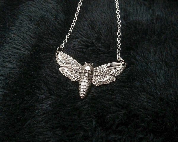 A silver necklace with a death's head moth charm.