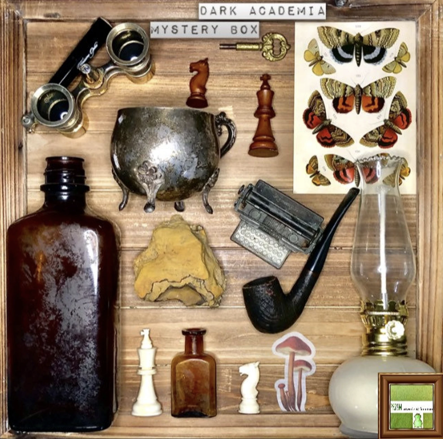 A flay lay of some dark academia knick knacks including chess pieces, a pipe, amber bottles, and more