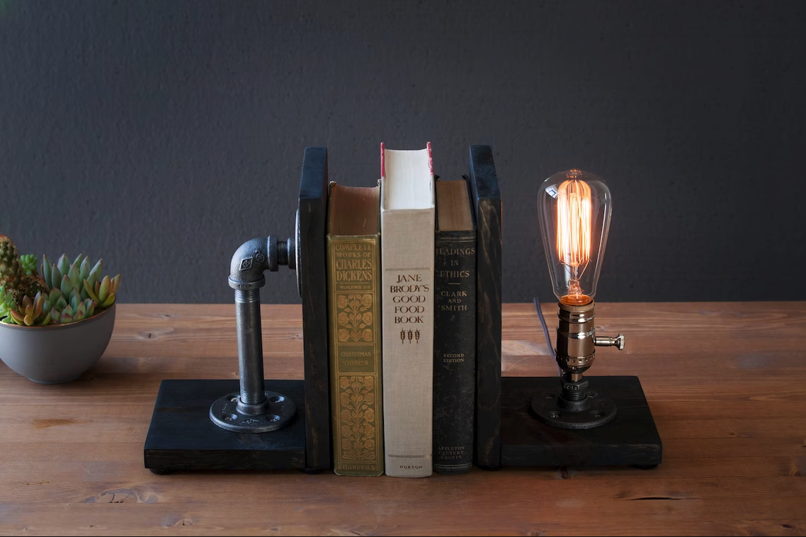Steampunk bookends: on one side a metal pipe, on the other an edison bulb lamp
