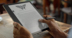 a photo of someone using a Kindle Scribe, a large e-ink ereader