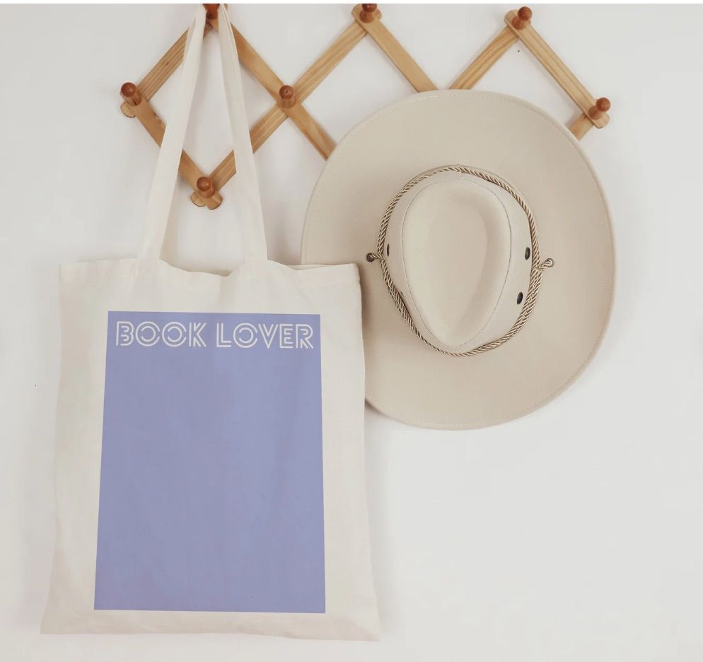 Image of a tote bag with a purple square on it. On the square is white text reading "book lover."
