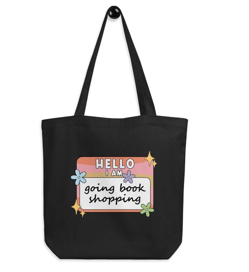 Image of a black tote bag with a "hello, I am" style sticker image on it that says "going book shopping."