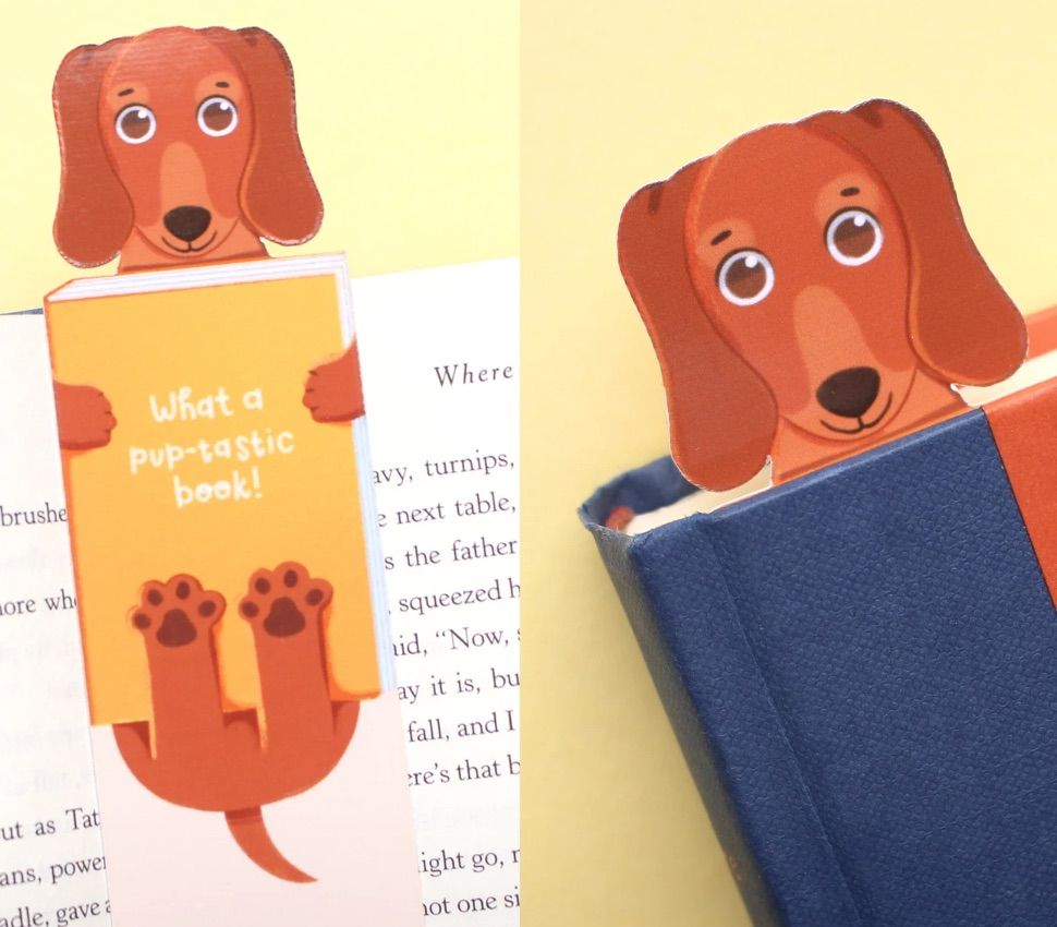 brown doxie bookmark. The dog is holding a yellow book that says "what a pup-tastic book!"