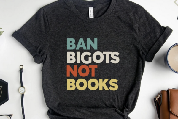 Black shirt with bold text in teal, white, red, and yellow reading "ban bigots not books"