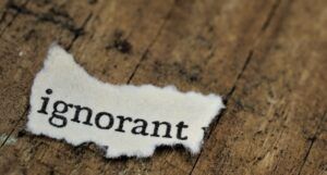 the word "ignorant" typed on a torn piece of paper