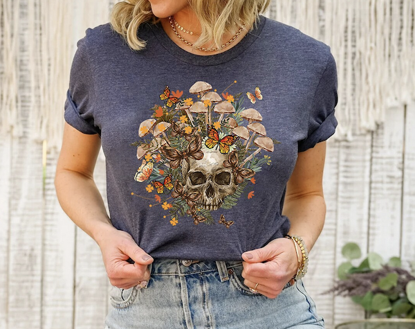 a t-shirt with a skull illustration and mushrooms and butterflies surrounding the skull