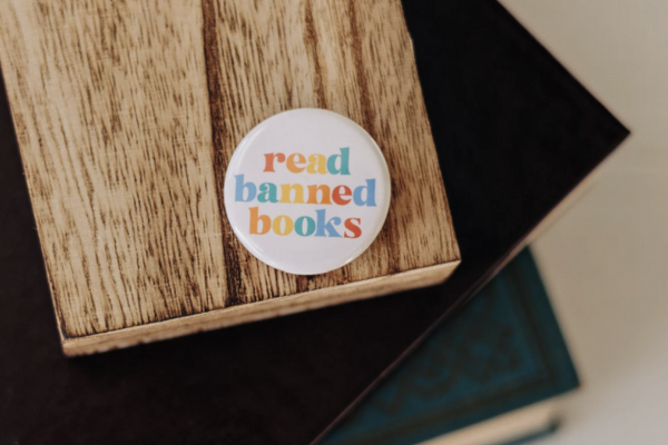 white circular button featuring rainbow text that says "read banned books"