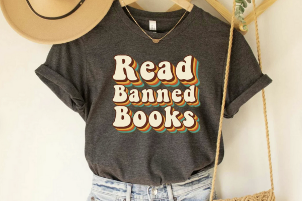 Gray tee shirt emblazoned with bubble letters with rainbow shadow reading "Read Banned Books"
