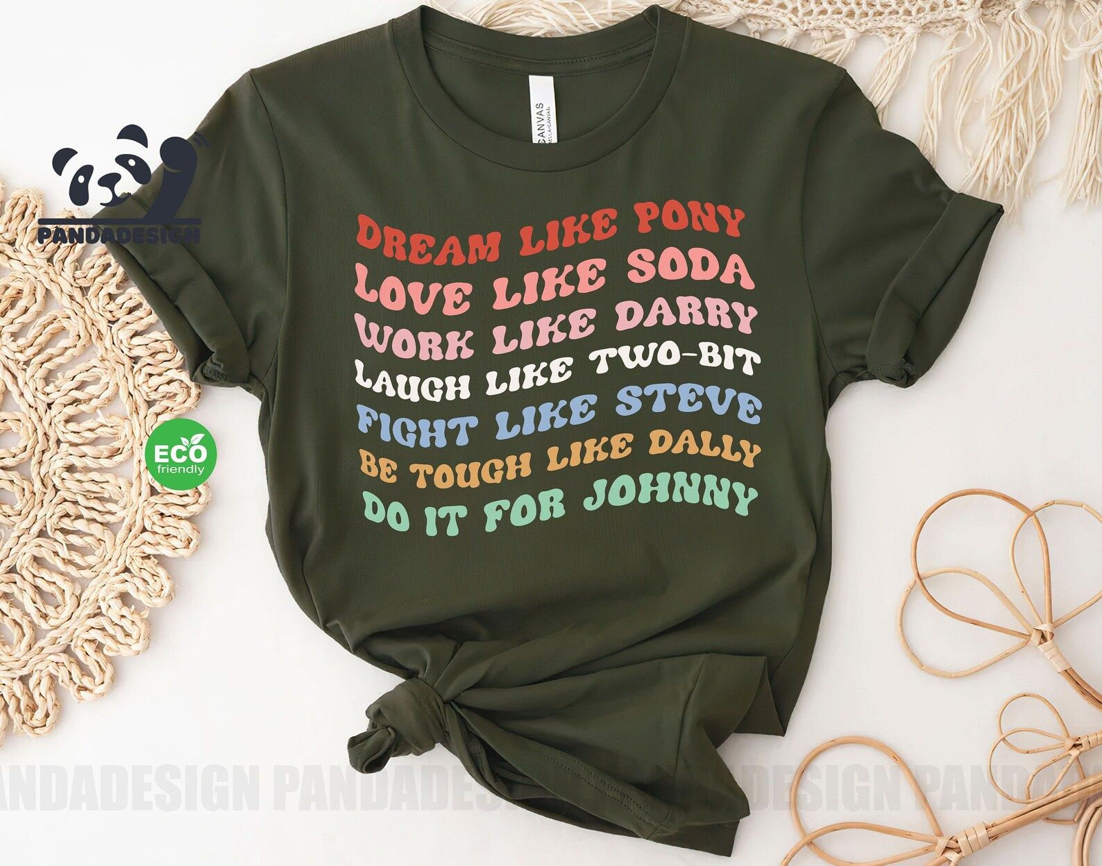 a black shirt in rainbow groovy test that reads : Dream Like Pony, Love Like Soda, Work like Darry, Laugh like Two-Bit, Fight like Steve, Be Tough by Dally, Do it for Johnny.