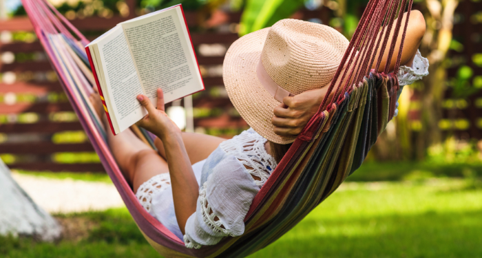 a photo of someone wearing a floppy hat and reading in a hammock