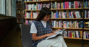 Asian woman with long hair sitting and reading in a library