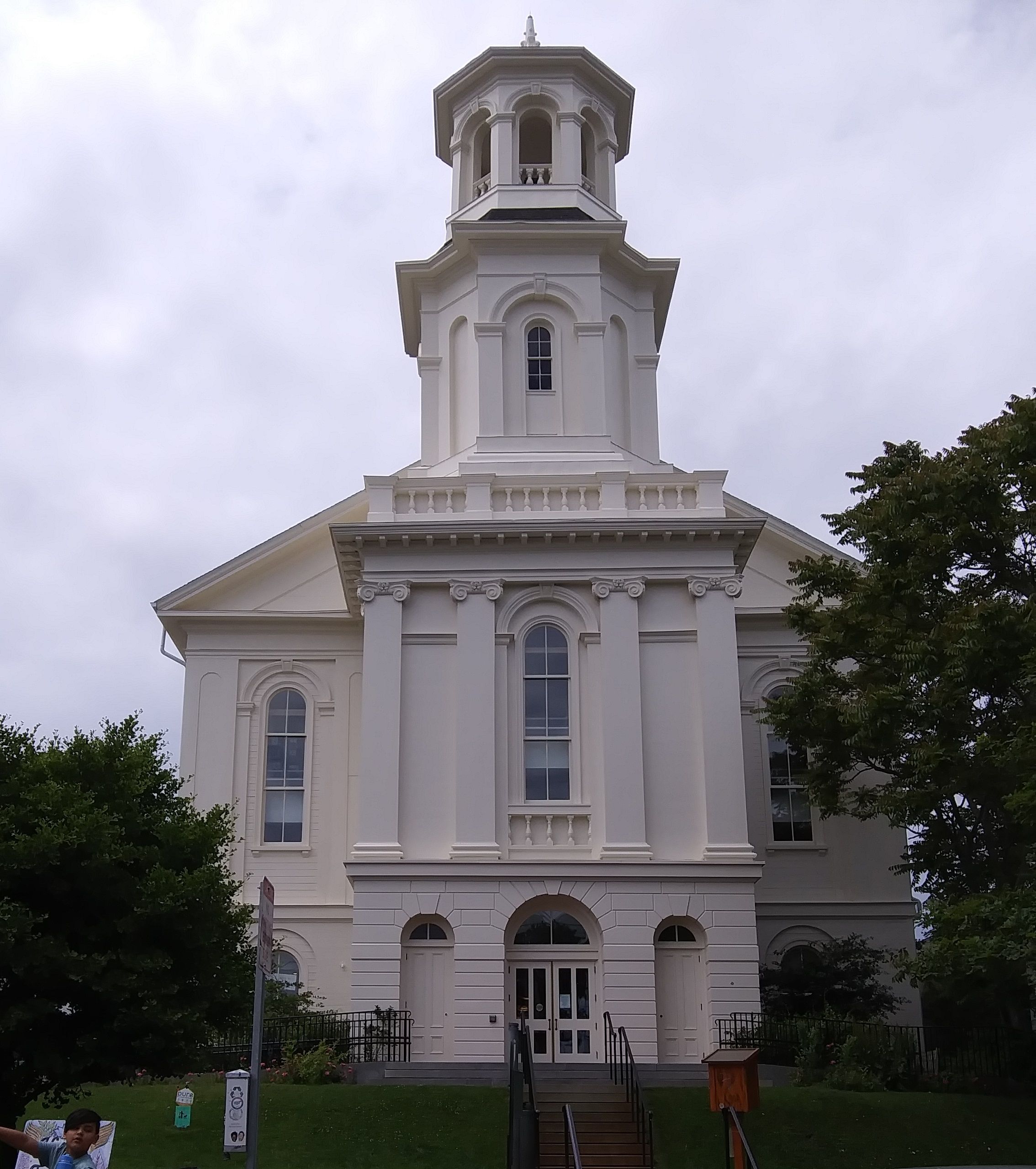 A front view of the Provincetown Library, a white former Church complete with a steeple on top