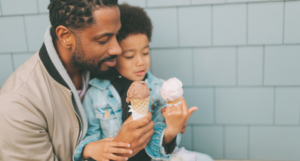 a photo of a Black father and son eating ice cream cones
