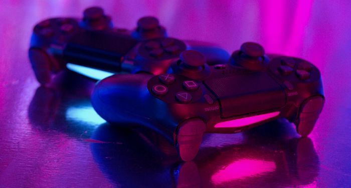 closeup of two black game controllers in neon purple light