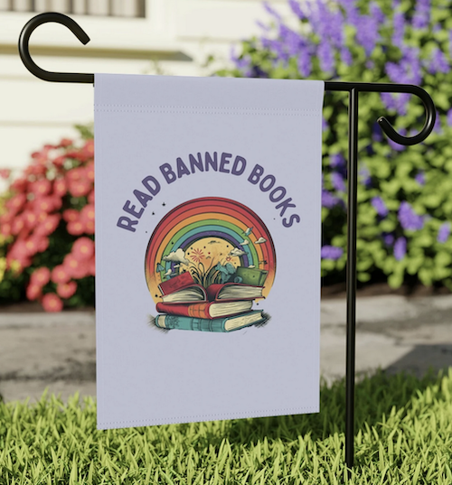 a garden sign with a rainbow and book illustration that says Read Banned Books