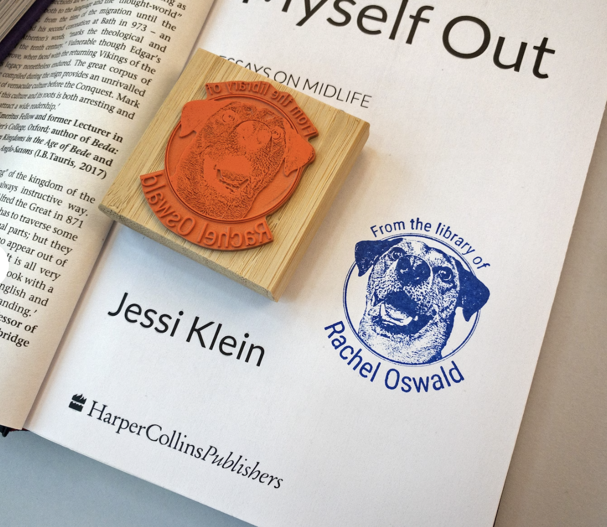 An open book displaying a rubber stamp with a dog's face and the text "From the Library of Rachel Oswald", along with a print from the stamp in blue ink.