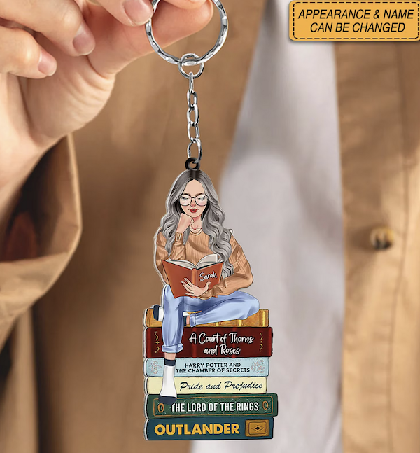 acrylic keychain with illustration of a young white  woman sitting on a stack of books that can be customized