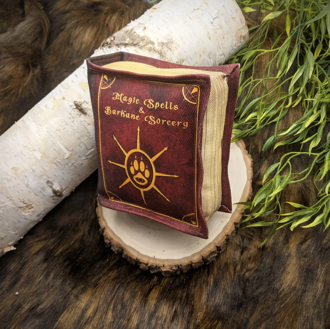 A stuffed dog toy shaped like a book with the title "Magic Spells and Barkane Sorcery"