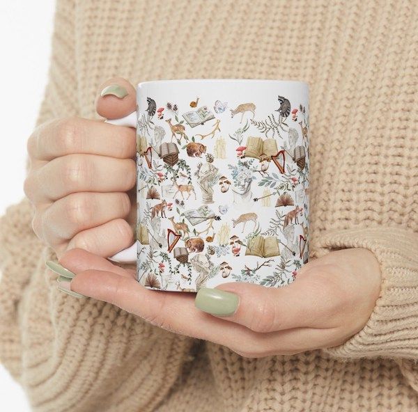 white mug covered in images of plants, animals, open books, and greek statue busts