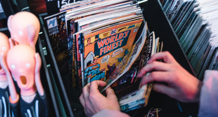 a photo of someone flipping through a bin of comics