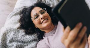 Image of a person with olive skin and glasses reading on an ereader