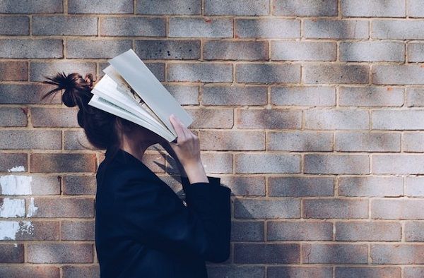 a photo of a person holding a book over their face