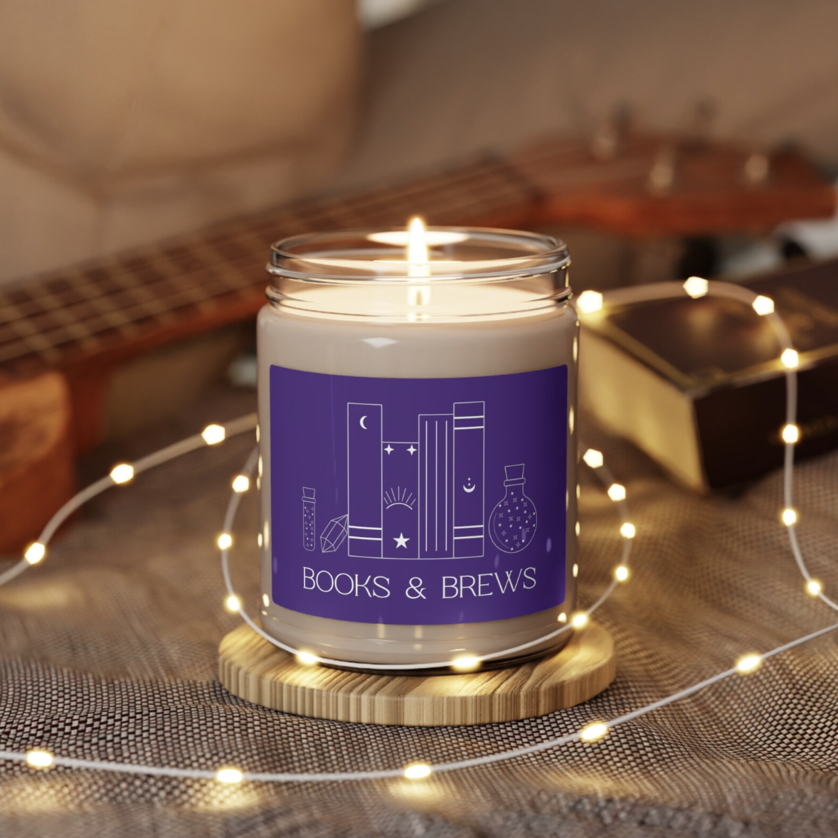 A candle in a jar with a purple label that says "Books & Brews" with an illustration of several books