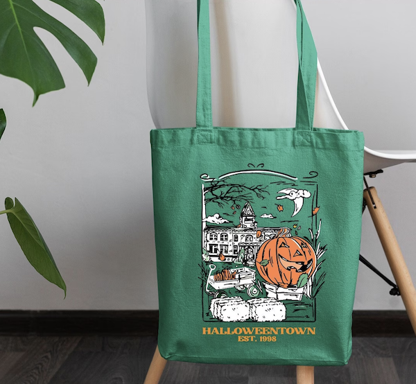 green tote bag with a graphic print image of a pumpkin in the foreground with a university in the background