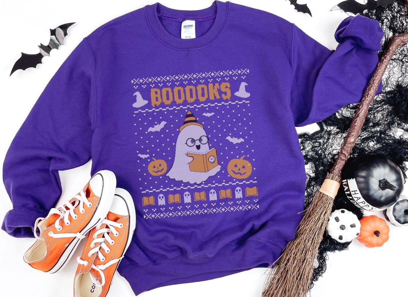 A halloween sweatshirt themed like an ugly Christmas sweater, featuring a ghost reading and the word "booooks."