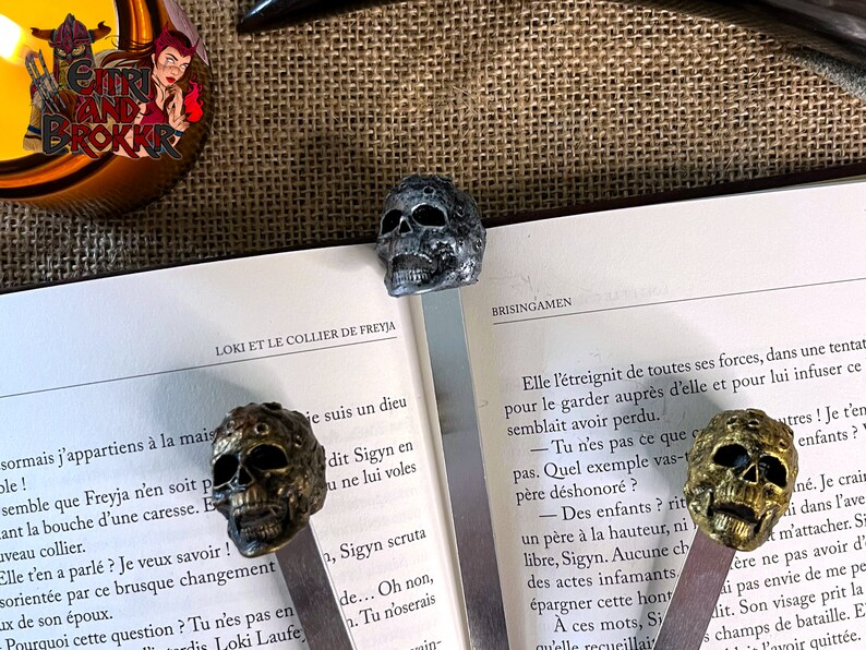 Photo of three resin skulls bookmarks placed on an open book. 