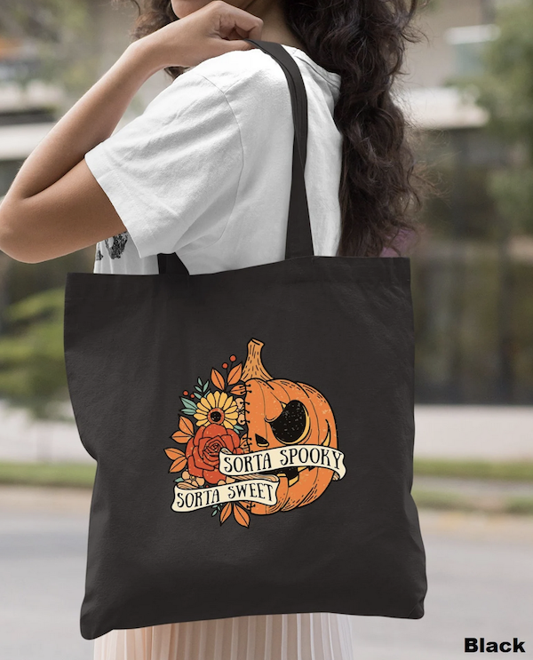 black canvas tote bag with a pumpkin flower design and letting that says "sort spooky sorts sweet"